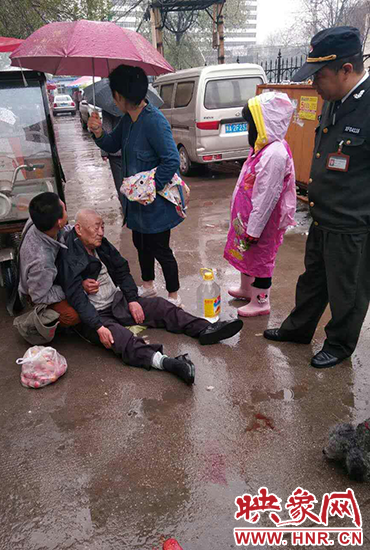 女孩為倒地老人撐傘。