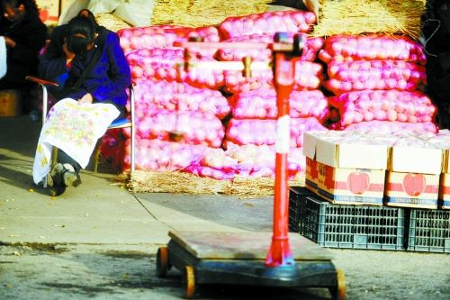 水果批發(fā)市場(chǎng)內(nèi)，沒(méi)有客戶時(shí)，商戶在繡十字繡