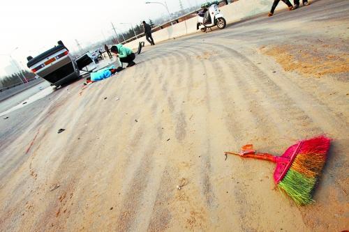 被撞的環(huán)衛(wèi)工躺在地上，身上蓋著藍(lán)色布塊，現(xiàn)場除散落的汽車碎片外，還留有被撞斷的掃帚。