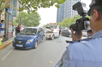 在金水路，交警對在機(jī)動車道違法停放的車輛施行拖離