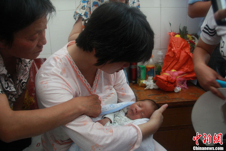 圖為久別重逢，獲救嬰兒母親悉心撫摸愛子。張一辰 攝