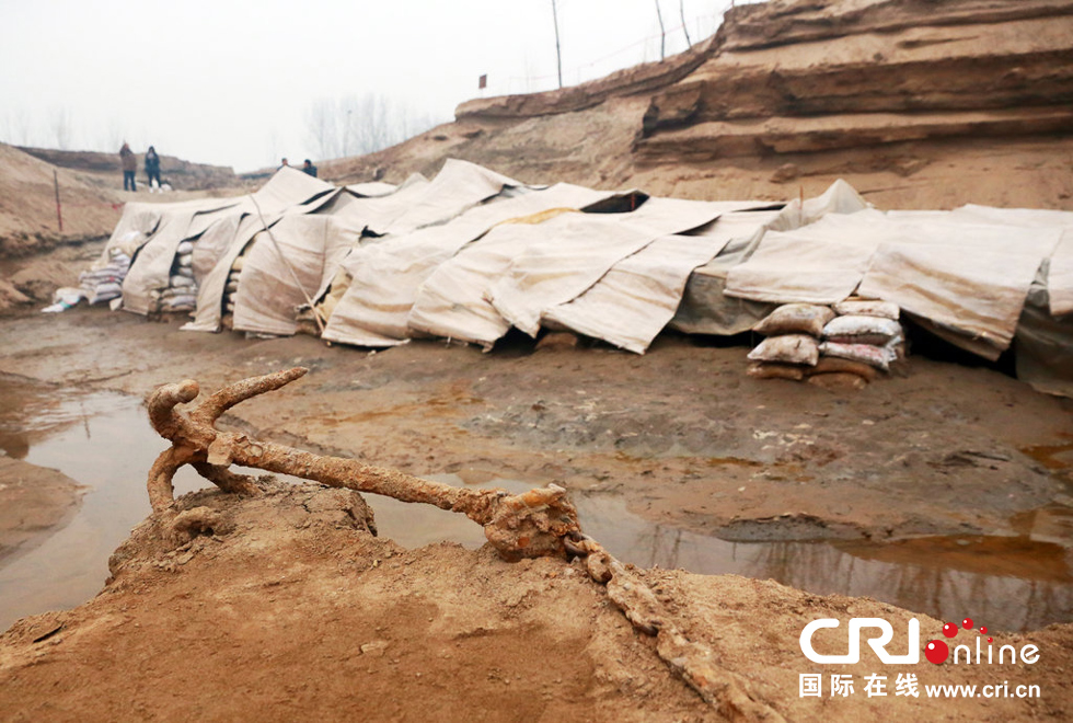 2014年1月6日，河南洛陽古沉船發(fā)掘現(xiàn)場，古沉船鐵錨從見天日，靜靜地躺在古船旁。