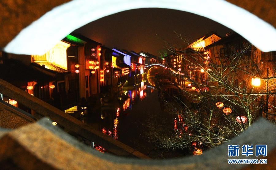 1月30日透過(guò)蘇州市新民橋孔拍攝的山塘古街水巷夜景。