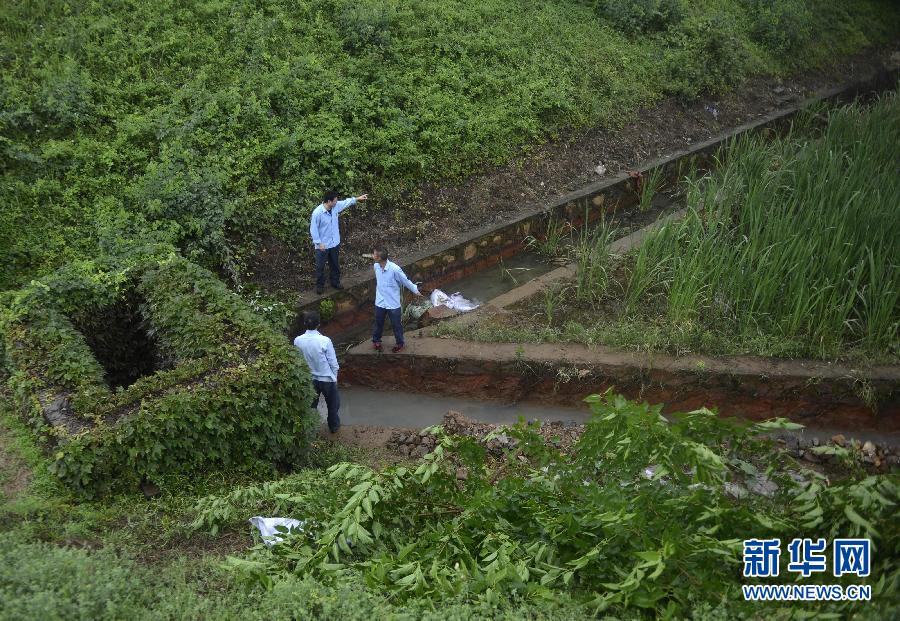 5月18日，工作人員在槽罐車泄漏現(xiàn)場附近的水渠邊查看情況。