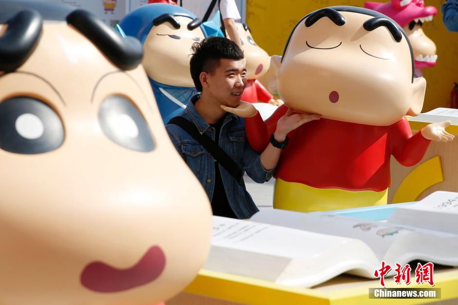 4月22日，游客與蠟筆小新合影?！跋灩P小新25周年紀(jì)念特展”日前在北京開(kāi)展，吸引了不少市民游客。