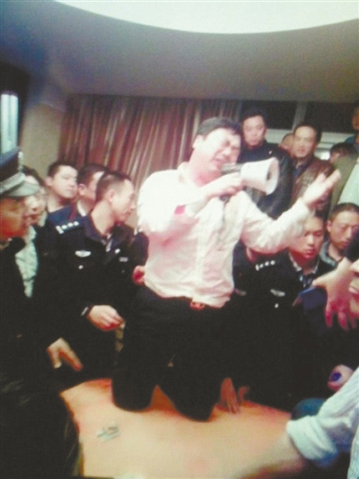 　4月19日，泰州市濱江工業(yè)園區(qū)管委會招待中心，一男子跪在酒桌上喊話求饒。李根 攝