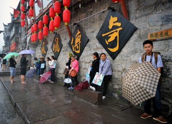 　4月29日上午11時(shí)20分，一些游客和古城當(dāng)?shù)氐木用穸阍谝粋€(gè)酒吧的屋檐下避雨。這些當(dāng)?shù)鼐用褚詾橛慰团恼罩\生，一場(chǎng)降雨讓他們的生意更加清淡。