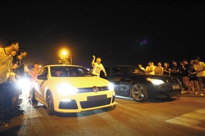 8月24日晚，東壩中街飆車現(xiàn)場，兩輛車并排等待出發(fā)指令，旁邊許多愛好者前來觀看比賽。新京報記者