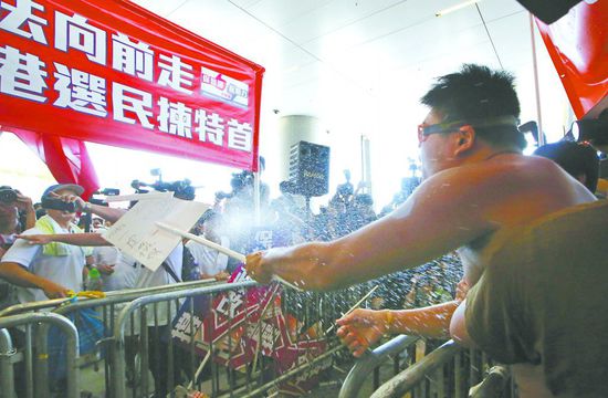 17日，在香港立法會(huì)外，一名反對(duì)政改的男子向支持派人群投擲標(biāo)牌。