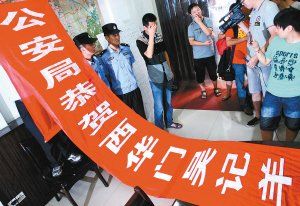 面對(duì)警方收繳的條幅，老板楊某也不好意思地用手遮擋臉