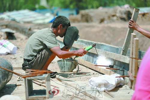 　正午陽(yáng)光下，工地上的焊接工人還在認(rèn)真工作。