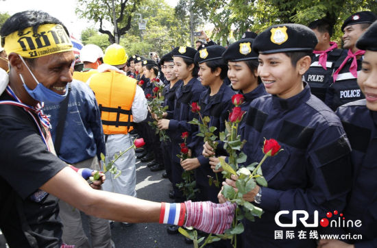 2013年12月03日,曼谷總理府與曼谷警署允許反政府示威民眾進(jìn)入,雙方進(jìn)入暫時(shí)“停戰(zhàn)”狀態(tài)迎接泰王生日。曼谷警察總署,女警們手持鮮花送給反政府示威民眾。圖片來(lái)源:Manish Swarup/東方IC