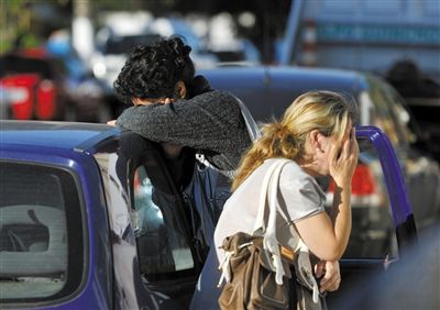 27日，遇難者親友在火災現(xiàn)場旁哭泣。