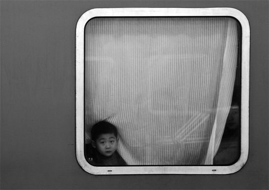 一個孩子把頭伸向窗外，他想再看送別的親人一眼