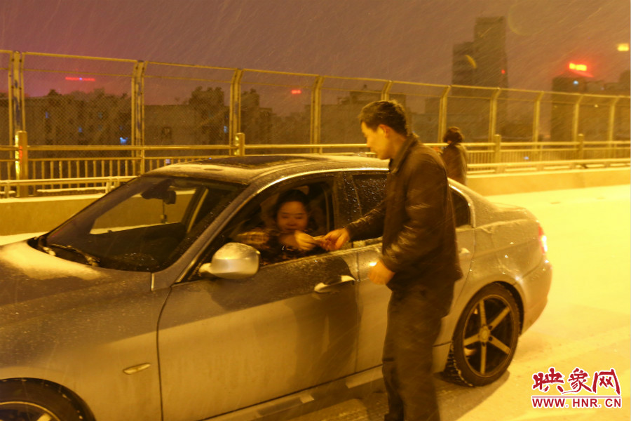 “推車人”幫助一輛車上坡后，收取“勞務(wù)費”。