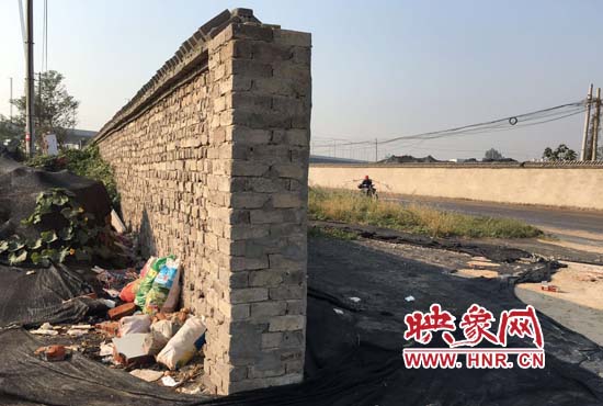 一墻之隔，一邊是道路，一邊是垃圾和荒草，市民質(zhì)疑其為遮羞墻。