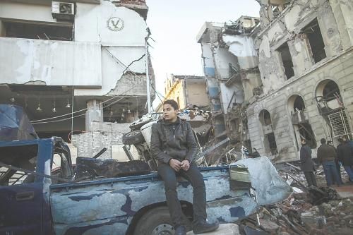 埃及曼蘇拉市警察局24日遭汽車炸彈襲擊，被疑是穆兄會的報復(fù)。圖為一名男子在被炸毀的警察局前。