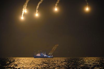 22日，搜救人員在照明彈的光亮下連夜搜救。