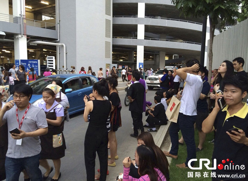 當?shù)貢r間2014年5月5日，泰國清萊，工人們站在一棟大樓外避難。