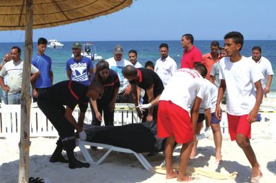 6月26日，在突尼斯蘇塞，救生員和醫(yī)務(wù)人員在發(fā)生襲擊事件的海灘運送一名死者的遺體。新華社發(fā)