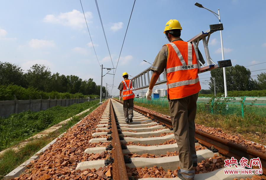 滾燙的鐵軌上，兩個扛著梯子的檢修員走向第四個檢修點