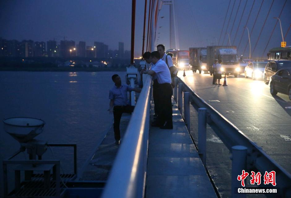 圖為武漢警方談判專家正在與翻爬至大橋外側(cè)護(hù)欄的劫持者談判。