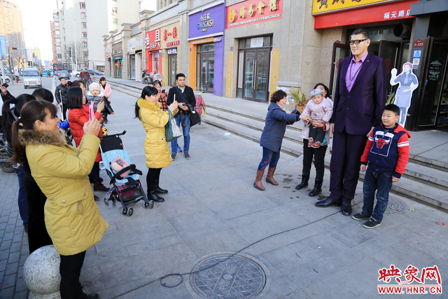 過路市民爭相與“巨人”合影。