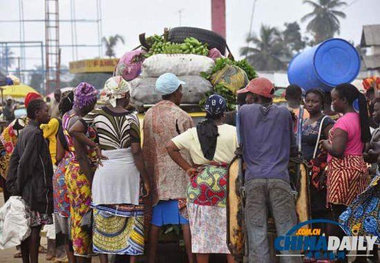 當(dāng)?shù)貢r(shí)間2014年8月14日，利比里亞蒙羅維亞，市場(chǎng)里的商人們圍著一輛汽車。