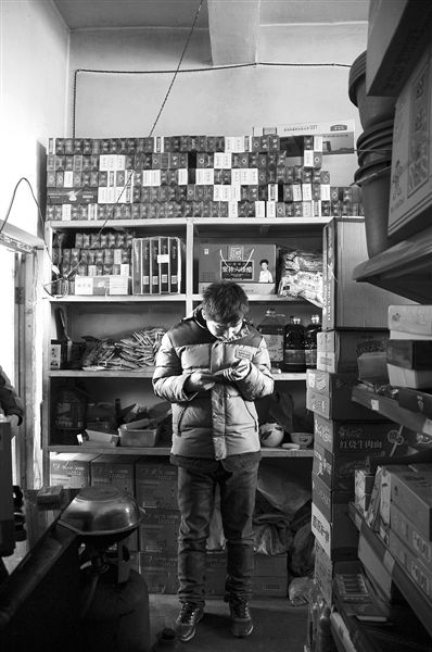 1月21日，周瑋在自家的超市里玩計(jì)算器。