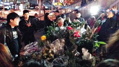 昨晚7時許，三里屯太古里西邊附近一過街天橋旁邊，聞訊而至的網友圍住了賣花老人，爭相買花。 網友“行者橙子”供圖