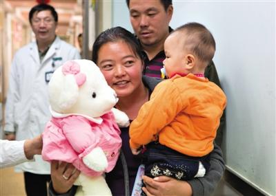 昨日上午，被扎針女嬰的母親抱著孩子和醫(yī)護人員送的玩偶準備出院，院方稱孩子術后恢復良好。記者 高瑋 攝