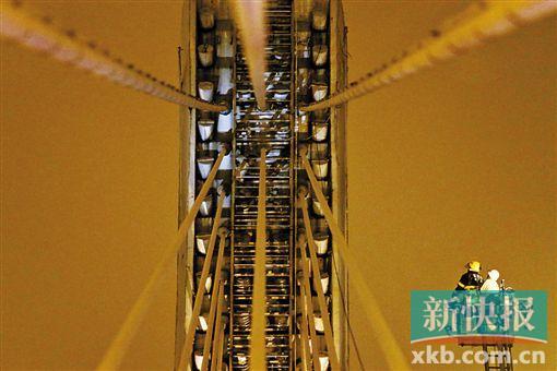 截至今日零時(shí)，男子仍未有下橋舉動(dòng)。圖為公安和消防人員乘消防云梯在高空上和男子交談。