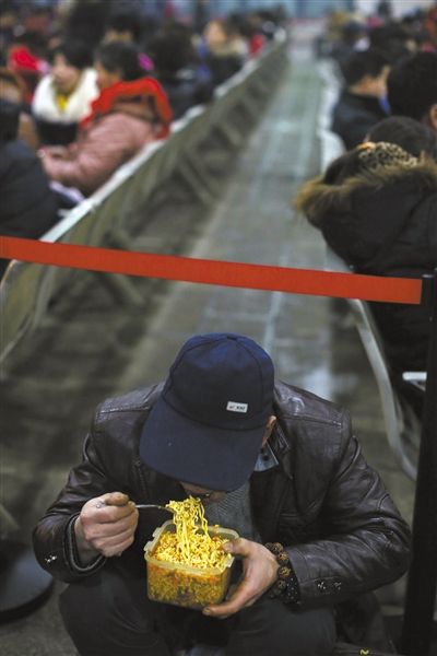 北京西站臨時候車廳，鄧軍吃著妻子泡好的方便面